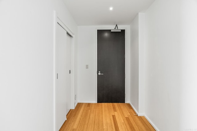 corridor with light wood-type flooring and baseboards