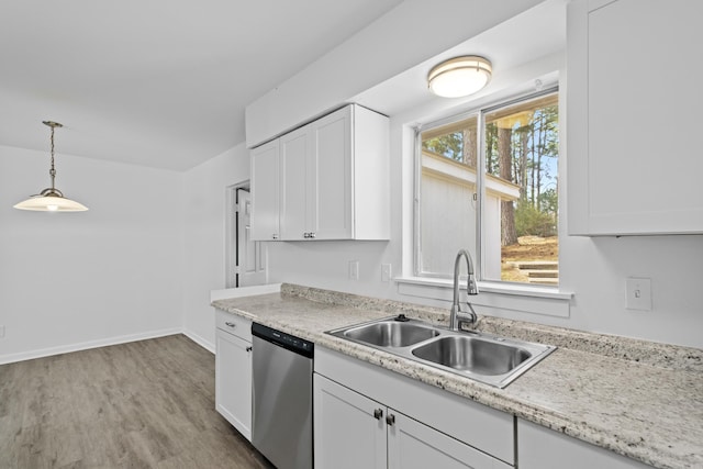 kitchen with light countertops, stainless steel dishwasher, white cabinets, a sink, and wood finished floors