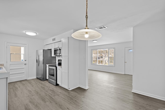 kitchen with stainless steel appliances, wood finished floors, visible vents, and white cabinetry