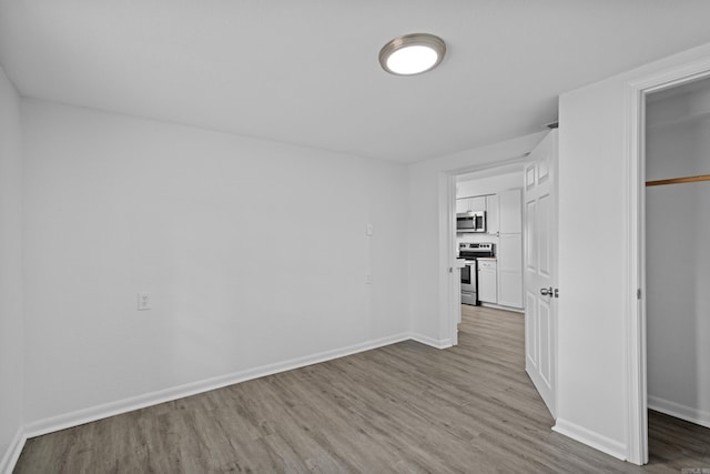 unfurnished bedroom with a closet, baseboards, and wood finished floors