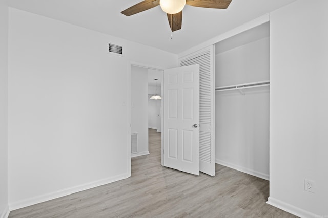 unfurnished bedroom featuring a closet, visible vents, baseboards, and wood finished floors