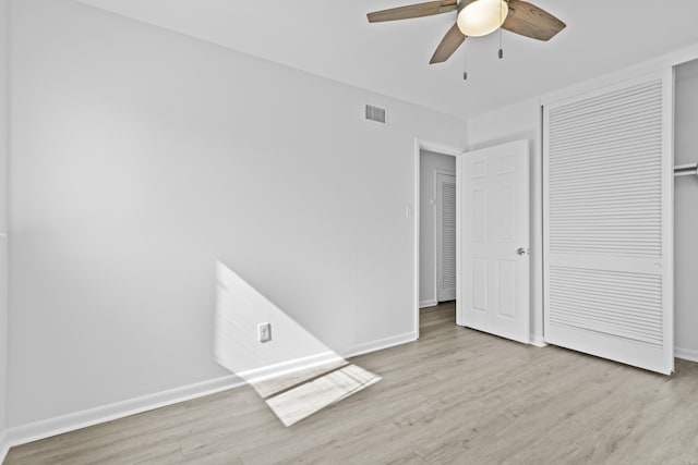 unfurnished bedroom with baseboards, a closet, visible vents, and wood finished floors