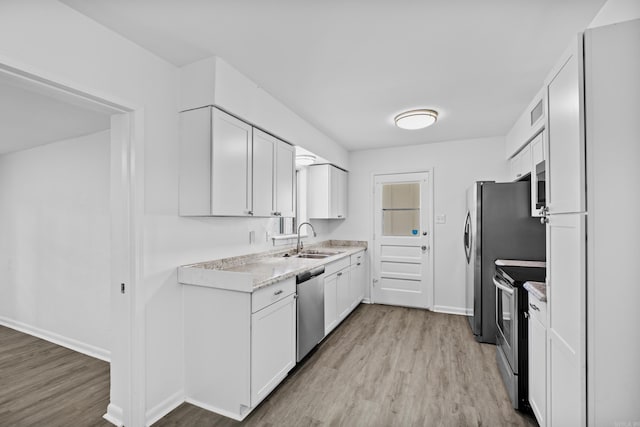 kitchen with light countertops, appliances with stainless steel finishes, a sink, and white cabinetry