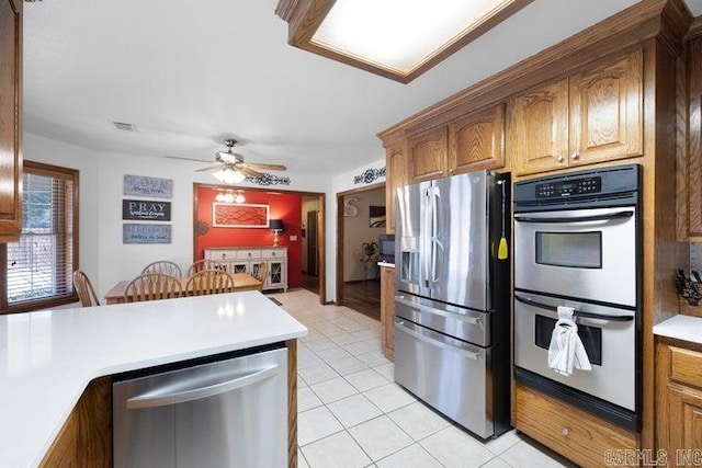 kitchen with light tile patterned floors, stainless steel appliances, light countertops, and brown cabinetry