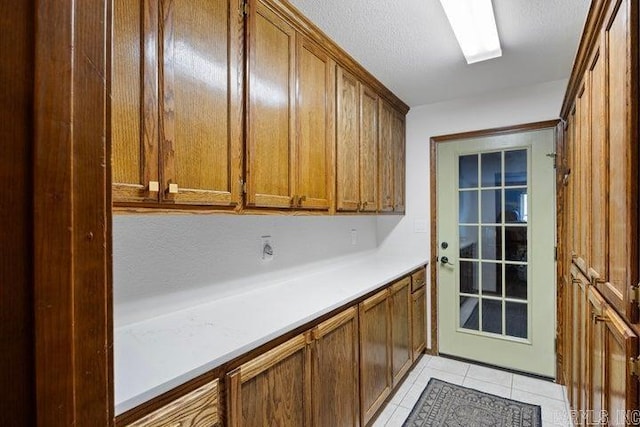 interior space with light countertops, brown cabinets, a textured ceiling, and light tile patterned floors