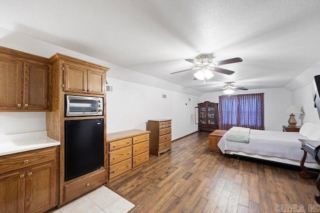 bedroom featuring a textured ceiling, lofted ceiling, visible vents, a ceiling fan, and light wood-type flooring