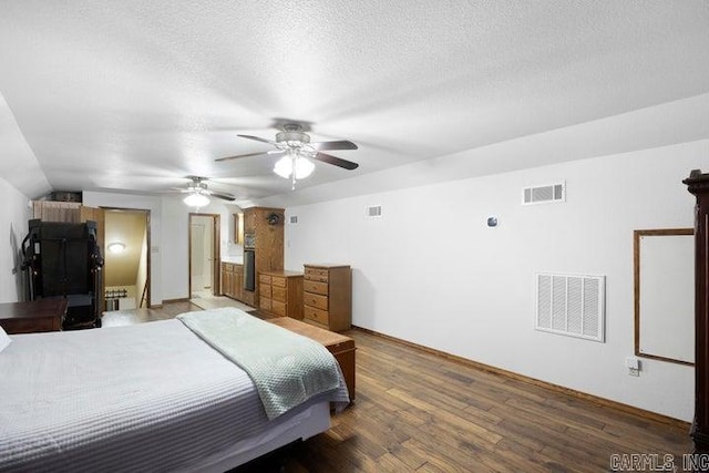 bedroom featuring a textured ceiling, ceiling fan, wood finished floors, and visible vents