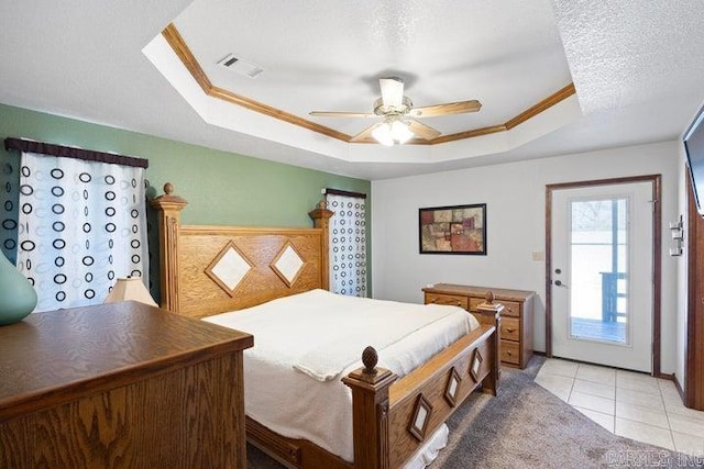 bedroom featuring visible vents, a tray ceiling, a textured ceiling, and ornamental molding