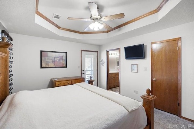 bedroom featuring ensuite bathroom, carpet floors, visible vents, a raised ceiling, and crown molding