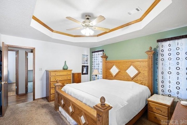 bedroom featuring visible vents, a tray ceiling, a ceiling fan, and ornamental molding