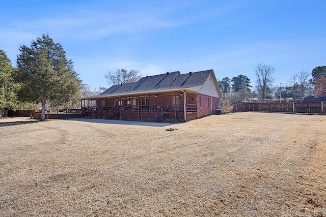 rear view of house featuring brick siding and fence