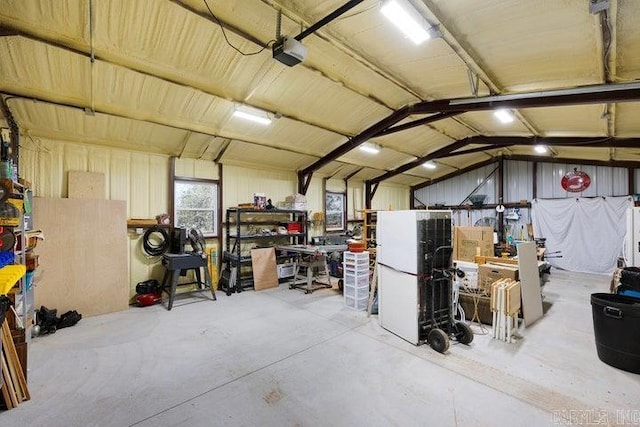 garage featuring metal wall, a workshop area, and a garage door opener