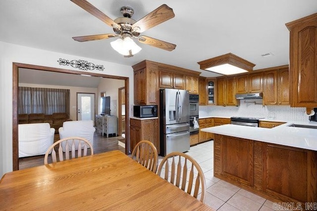 kitchen featuring stainless steel refrigerator with ice dispenser, a peninsula, black microwave, range, and under cabinet range hood