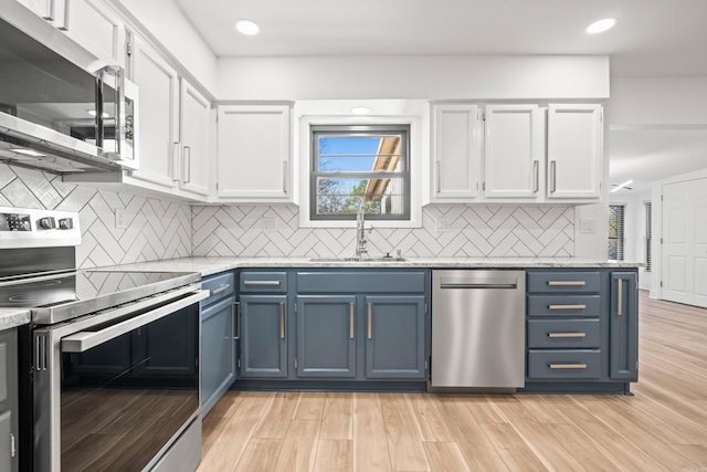 kitchen featuring blue cabinets, appliances with stainless steel finishes, white cabinets, and a sink