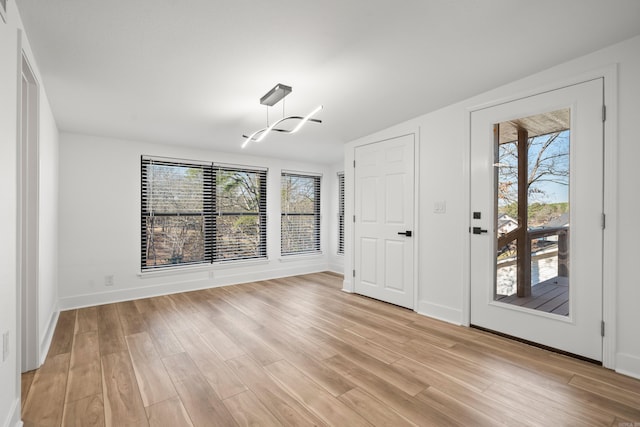 foyer with baseboards, a wealth of natural light, and light wood-style floors