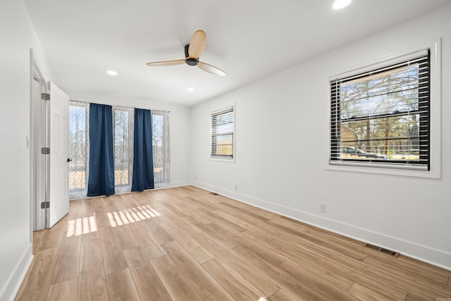 spare room featuring light wood-type flooring, visible vents, and baseboards