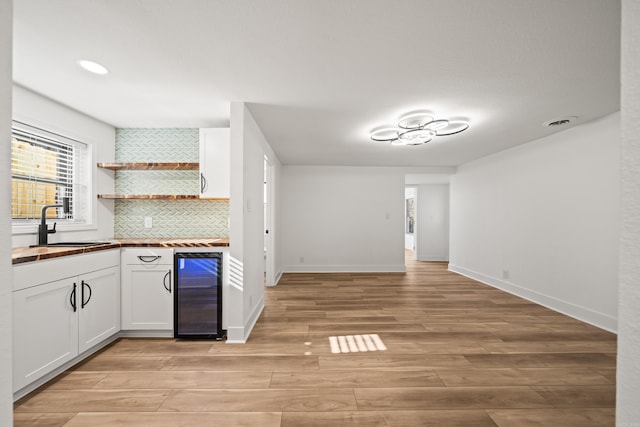 kitchen with light wood-style flooring, wine cooler, butcher block countertops, white cabinetry, and open shelves