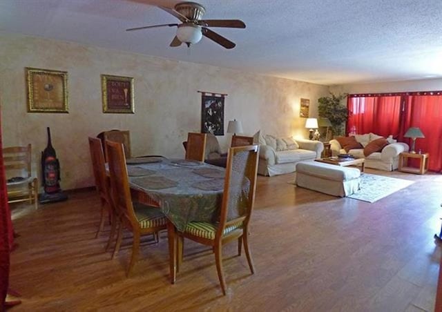 dining room featuring ceiling fan, a textured ceiling, and wood finished floors