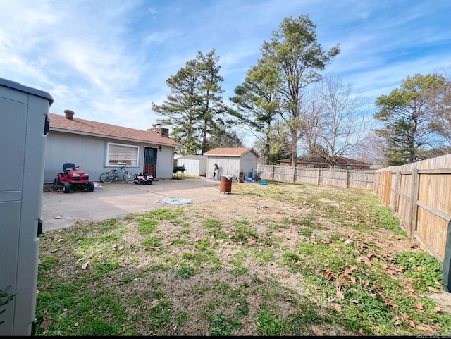 view of yard with a fenced backyard, a storage unit, an outdoor structure, and a patio