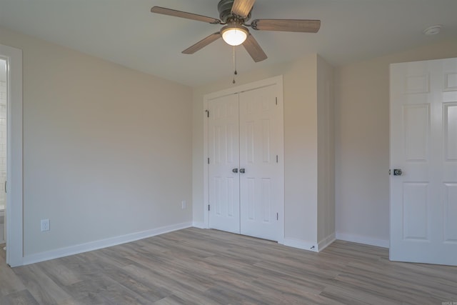 unfurnished bedroom with a closet, ceiling fan, baseboards, and wood finished floors