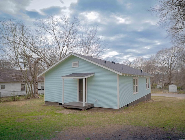 back of house featuring crawl space, fence, and a lawn