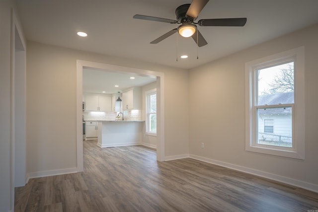 unfurnished living room with baseboards, ceiling fan, wood finished floors, a sink, and recessed lighting