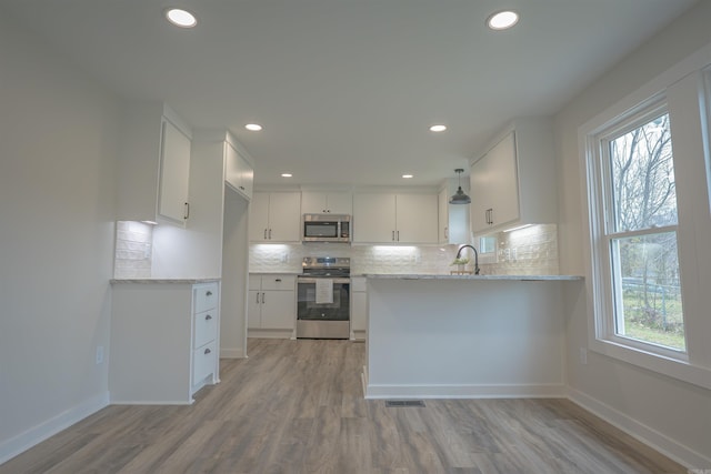 kitchen with appliances with stainless steel finishes, white cabinetry, and decorative backsplash