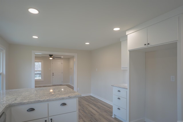 kitchen with baseboards, white cabinets, light wood-style flooring, light stone counters, and recessed lighting