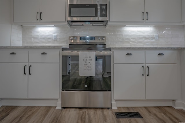 kitchen with white cabinets, light wood-style flooring, visible vents, and stainless steel appliances