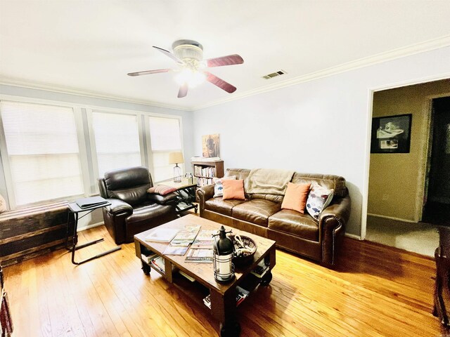 living area featuring a ceiling fan, visible vents, crown molding, and light wood finished floors