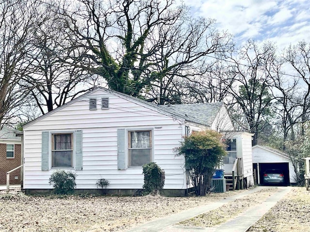 view of side of home featuring an outbuilding and roof with shingles