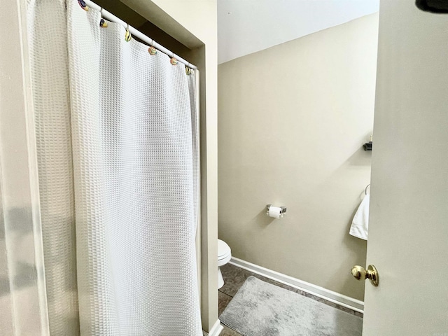 bathroom with curtained shower, tile patterned flooring, toilet, and baseboards