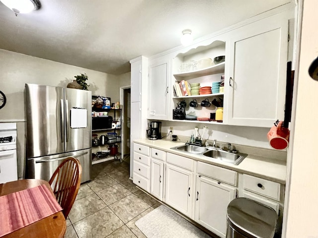 kitchen with white cabinets, a sink, stainless steel refrigerator with ice dispenser, and open shelves