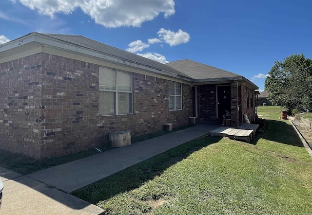 view of property exterior featuring brick siding and a lawn