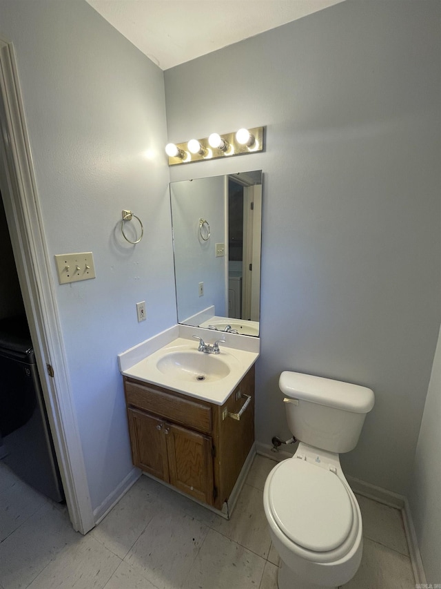 half bath featuring vanity, toilet, and baseboards