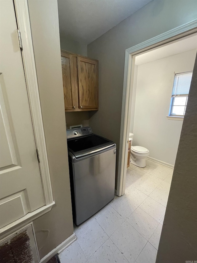 washroom featuring cabinet space, baseboards, washer / clothes dryer, and light floors