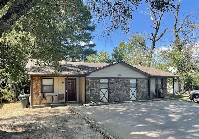 ranch-style house featuring stone siding and driveway