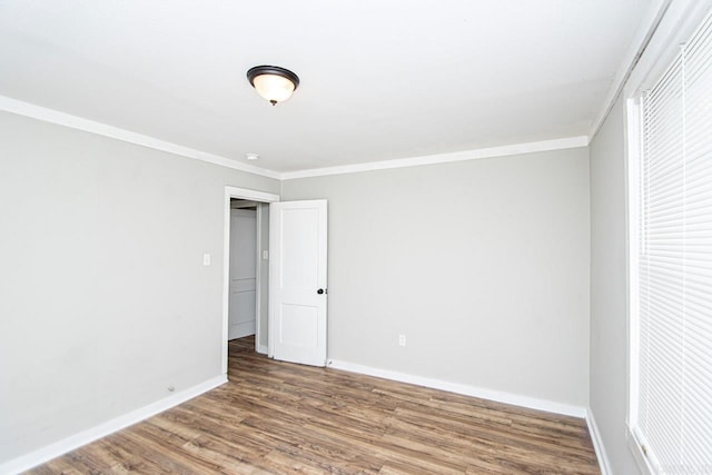 spare room with baseboards, ornamental molding, and wood finished floors