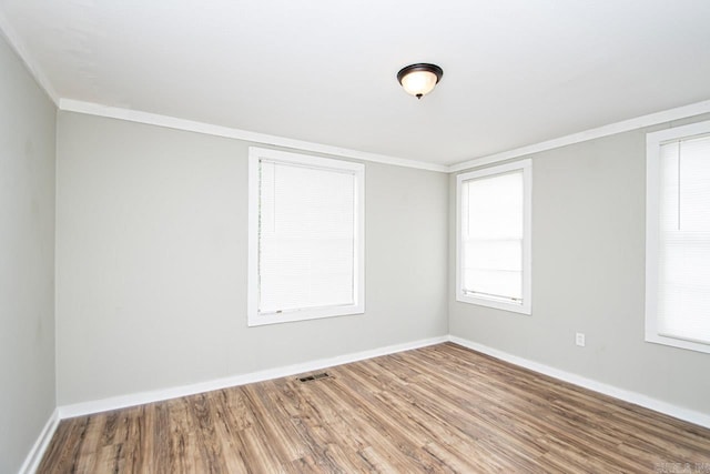 empty room with visible vents, crown molding, baseboards, and wood finished floors