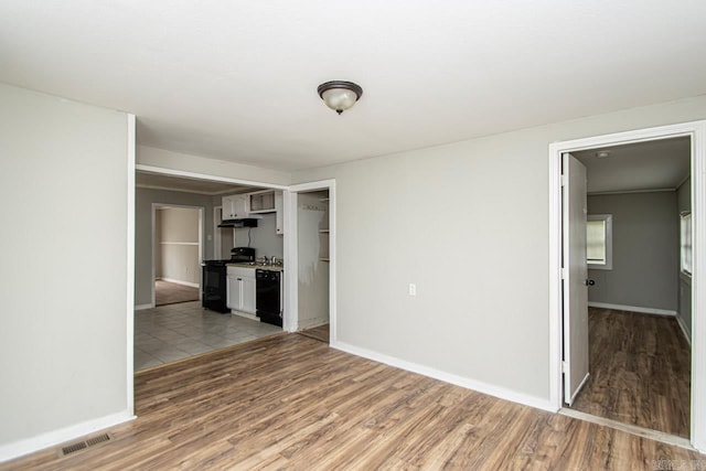 empty room with light wood-type flooring, visible vents, and baseboards