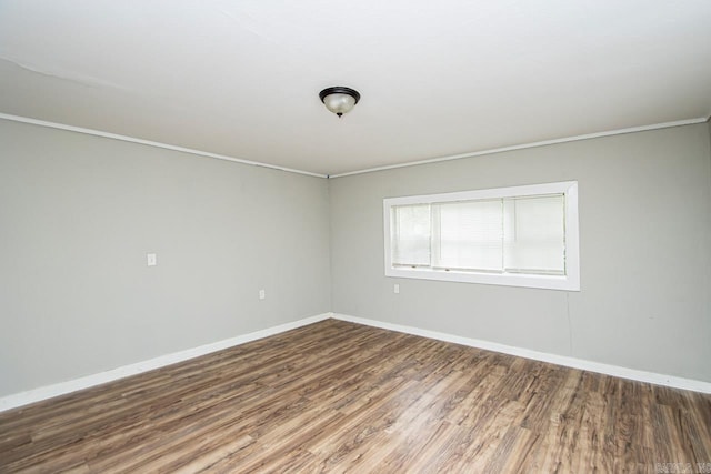 unfurnished room featuring baseboards, wood finished floors, and ornamental molding