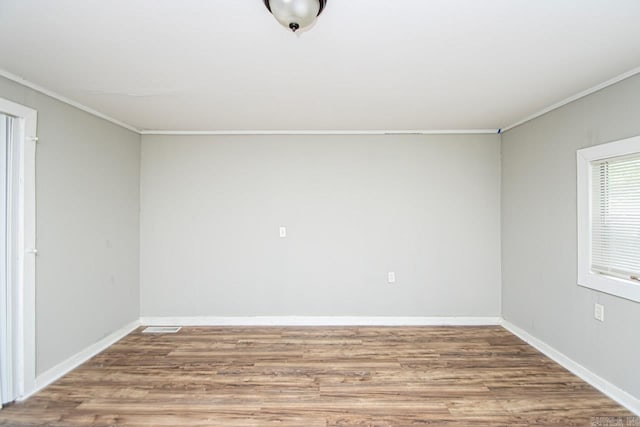 spare room featuring crown molding, baseboards, and wood finished floors