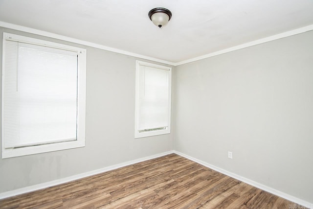 empty room featuring plenty of natural light, baseboards, wood finished floors, and ornamental molding