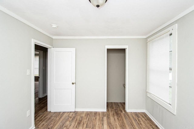 unfurnished bedroom with ornamental molding, a closet, wood finished floors, and baseboards