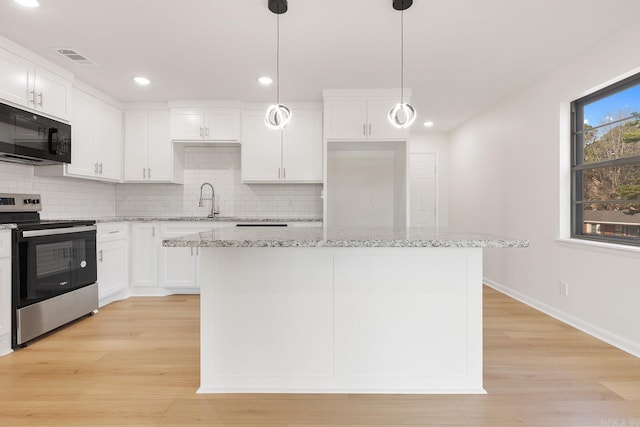 kitchen with black microwave, white cabinets, backsplash, and stainless steel range with electric cooktop