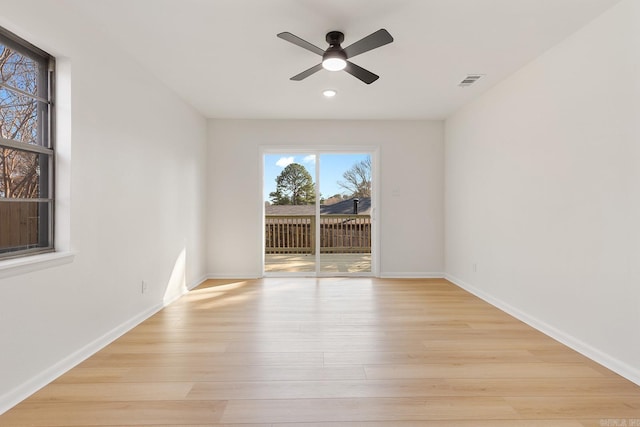 empty room featuring light wood-type flooring, visible vents, ceiling fan, and baseboards