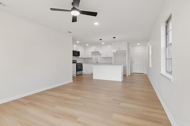 unfurnished living room with recessed lighting, visible vents, light wood-style floors, a sink, and baseboards