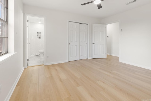 unfurnished bedroom featuring visible vents, baseboards, light wood-style floors, a closet, and ensuite bath