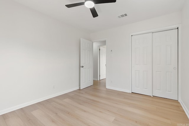 unfurnished bedroom featuring a closet, visible vents, light wood-style flooring, ceiling fan, and baseboards