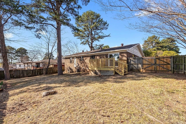 rear view of house with a fenced backyard, a gate, and a yard